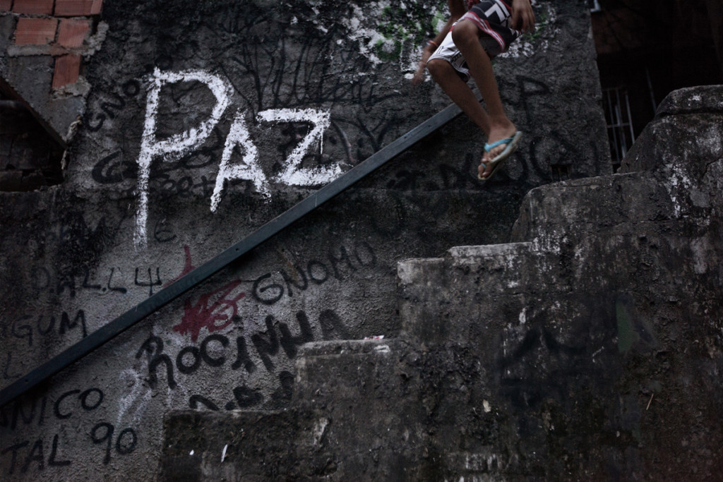 A youth jumps down a stairway with the word "peace" written on the wall, in the Shantytown of Rocinha, the biggest slum of Rio de Janeiro, Brazil, February 22, 2012. Initiated in 2008, the UPP, short for Unidade de Polícia Pacificadora (in English, Pacifier Police Unit or Police Pacification Unit), is a new system of community policing in Rio de Janeiro’s favelas once run by drug traffickers.  While many believe that UPPs have helped quell violence by opening the doors of the favelas to public services such as legal electricity supply, garbage collection, education, public works and social assistance program, others see the pacification program as a temporary cover-up to security problems in Rio de Janeiro.